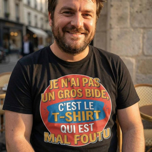 homme souriant portant un t-shirt humour avec le texte je n’ai pas un gros bide c’est le t-shirt qui est mal foutu
